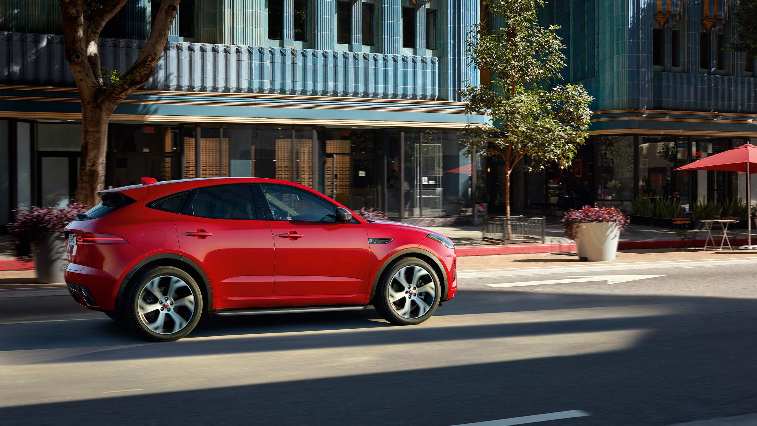 Jaguar E-PACE parked at the city road and a women seating an looking the looks of car